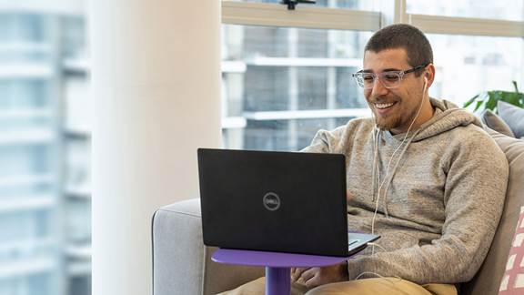 Employee smiling and working on a laptop