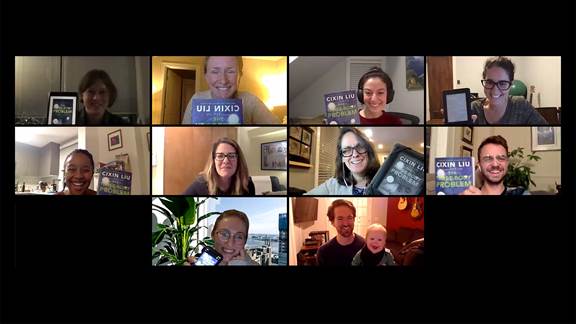 Image of employees smiling and showing their books in a book club Zoom meeting.