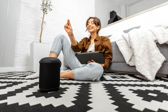 woman with a smart speaker and tablet at home
