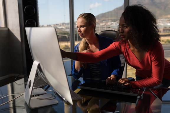 women working together pointing at desktop computer