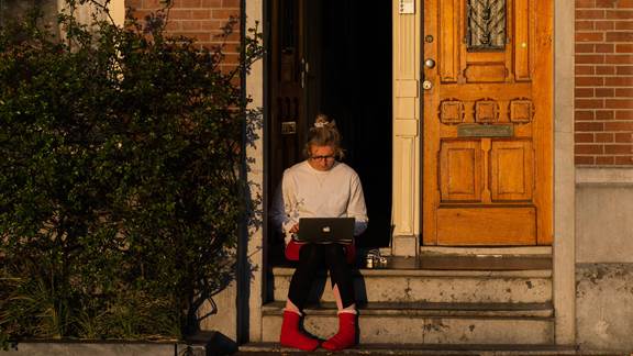 Woman sitting on doorstep with laptop