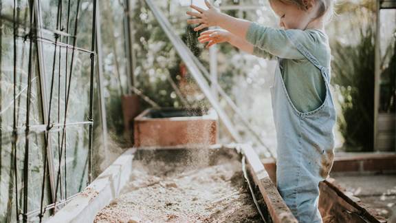 Little girl digging soil in a greenhouse
