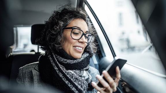 Woman smiling at her phone in the back of a taxi
