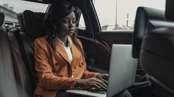 Woman typing on laptop in car