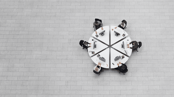 Circular table with six businesspeople working around it
