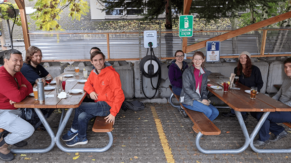 Group of individuals sitting at picnic tables, smiling at the camera