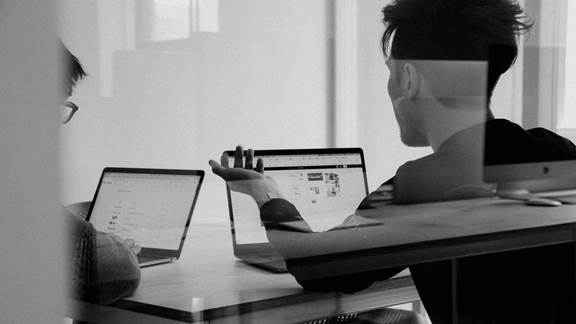 Two people discussing cloud at a desk on laptops