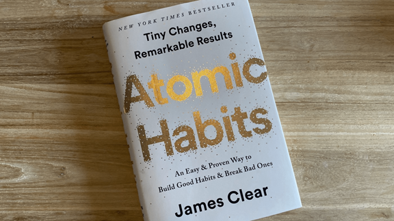 Atomic Habits by James Clear book on a wooden table