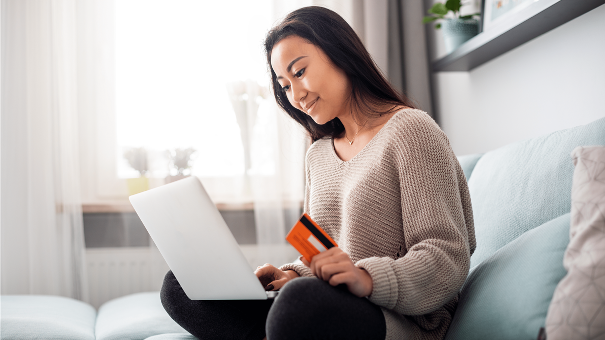 Woman looking at laptop with credit card in hand