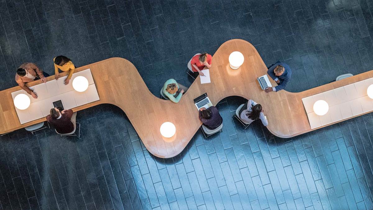 odd shaped desk with lamps and people working