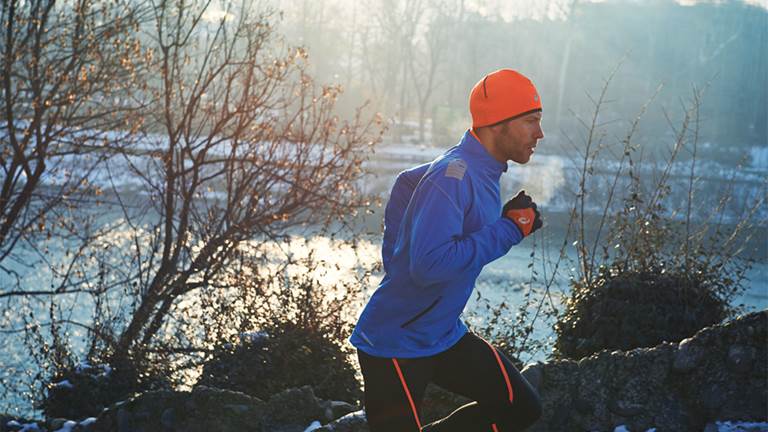 Young man running in the mountains in winter sports clothes