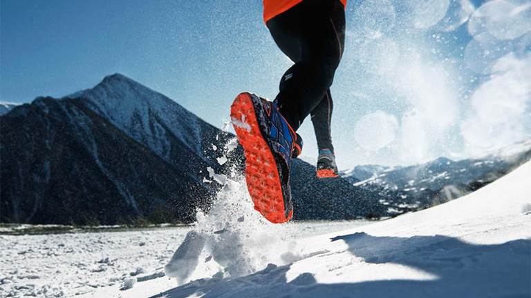 Close up of running shoe being used in snowy terrain