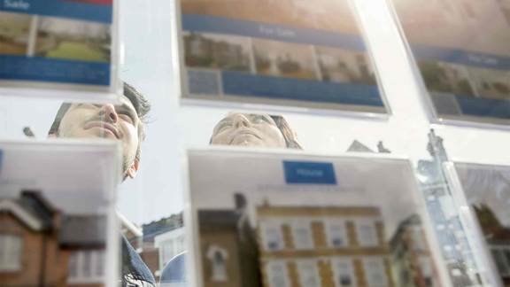 Couple-looking-at-displa-of-advertisements-in-estate-agent-window