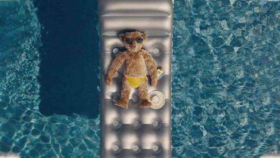 Edward Bear sunbathing in a pool