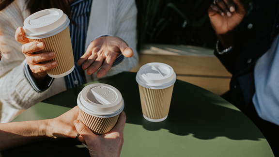 People holding disposable coffee cups at table