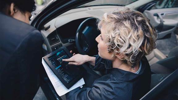 Image of woman in car with a tablet device conversing with another woman