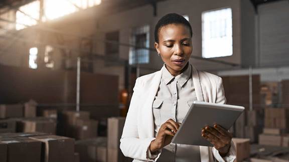 Female amazon partner holding tablet in warehouse of boxes