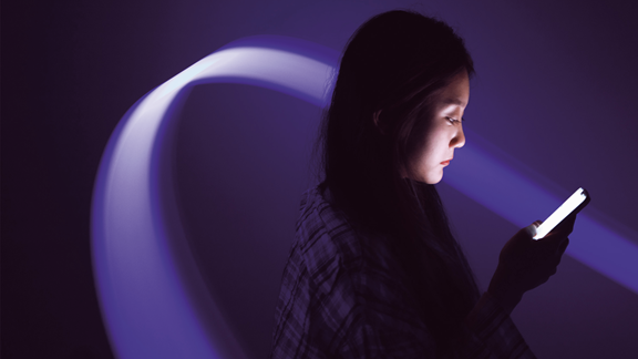 Woman looking at smartphone with purple lights