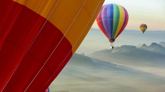 Colourful hot aire balloons floating between clouds in a beautiful sky