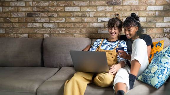 Female couple enjoying making internet purchases sitting on the couch