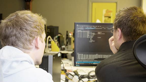 Two employees looking at a screen with code