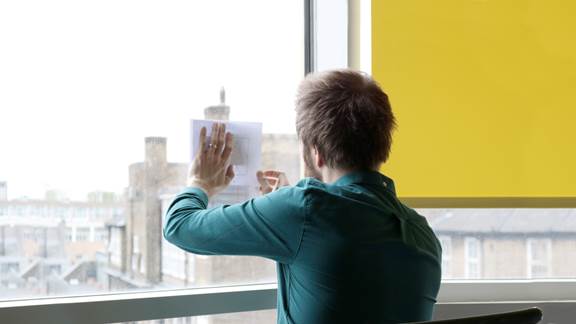 Man holding a piece of paper against a window