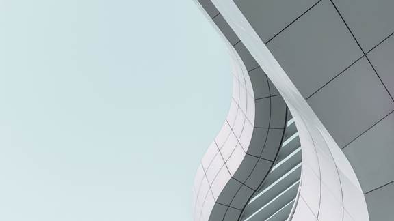 Modern building with curved facade over a clear blue sky.